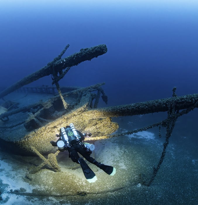 Diver approaching a shipwreck underwater.