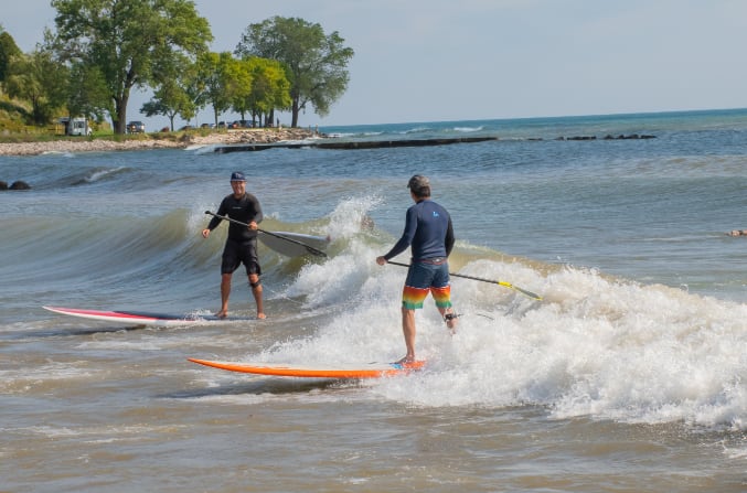 Two men surfing in a small wave.