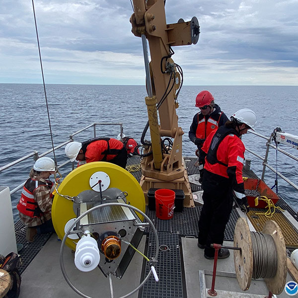 Group on the deck of a ship with various heavy equipment.