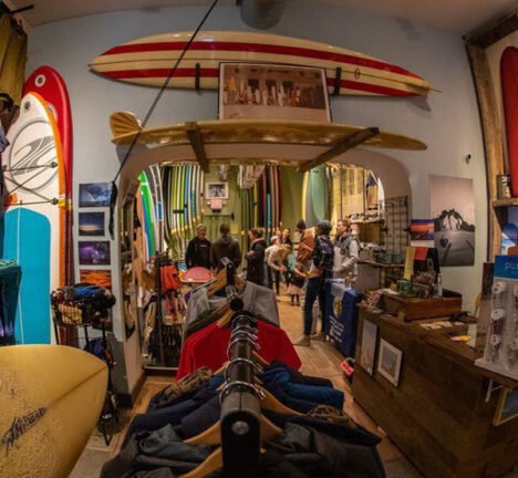 Interior of a surf shop with boards clothes and other merchandise.