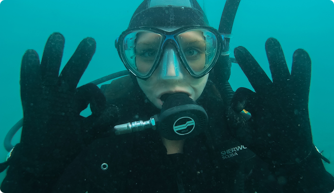 Close up of a diver giving an ok sign to the camera.