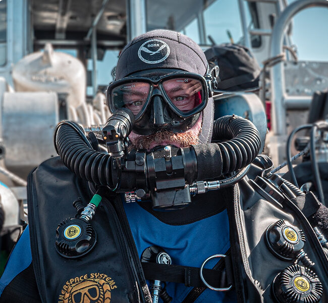 Portrait of a scuba diver in full gear standing on a boat.