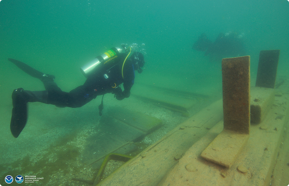 Scuba diver underwater with a shipwreck.