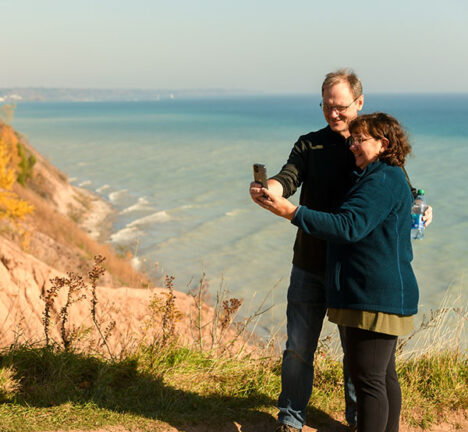 People taking a selfie on a cliff overlooking the beach.