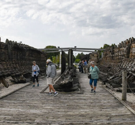 People walking inside a shipwreck on land.