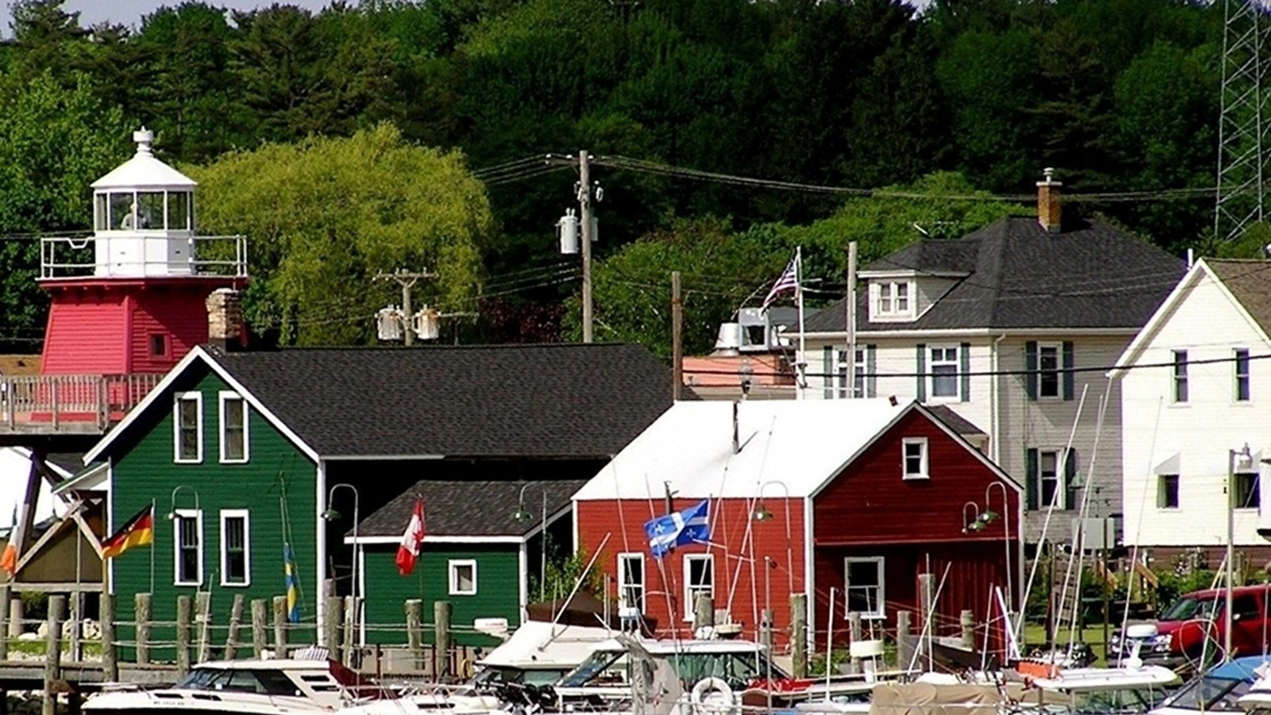 Coastal community buildings with boats in the foreground and a lighthouse.