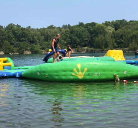 People climbing on inflatable platforms at a water park.